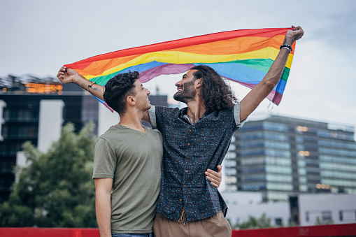 Male gay couple holding gay flag
