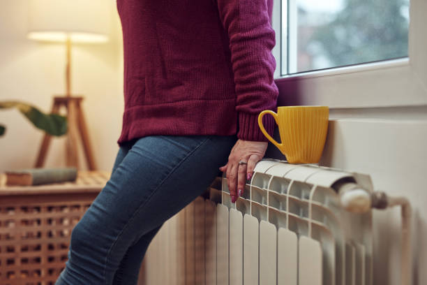 Woman heating on a chilly winter day, energy and gas crisis, cold room, heating problems. Woman heating on a chilly winter day, energy and gas crisis, cold room, heating problems. home heating stock pictures, royalty-free photos & images