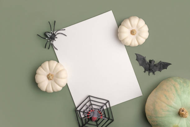 istock Blank paper sheet with Halloween decorations on pastel green background. Greeting card, invitation mockup. Place for inscription. Pumpkin. Modern Minimal business mock up, template. Flat lay, top view 1425811728