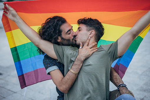 Male gay couple holding gay flag