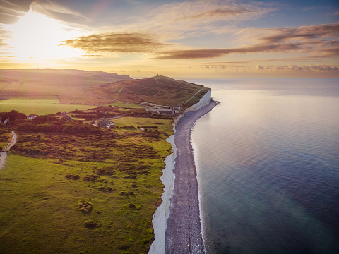 Aerial view, taken by drone, depicting a beautiful sunrise over the dramatic cliffs and coastline of the English south coast near Seven Sisters Country Park.