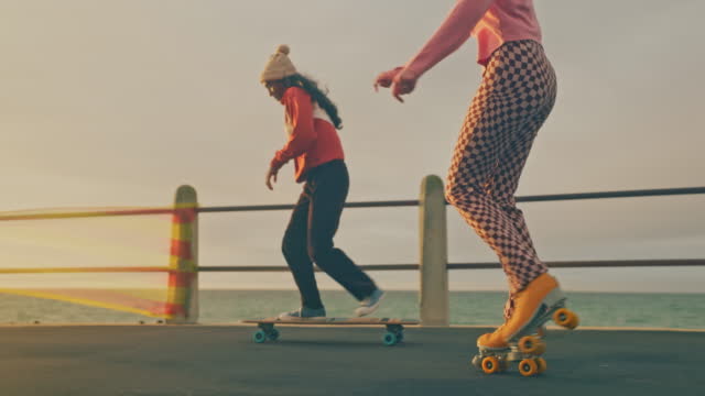 Friends, roller skates and beach travel with girls skating together on seaside promenade on holiday. Fun fitness activity, retro style fashion and summer friendship memories with skateboard skating