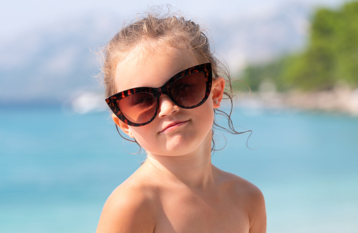 Portrait of a little girl with sunglasses on the sea.