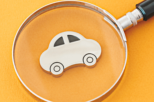 Magnifier over car model. Representing the search or reviews for car models, car rental options, car inspection,  financial solutions and insurances.
