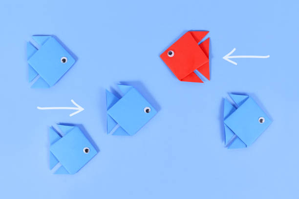 istock Red paper fish swimming swimming against the current 1425818538