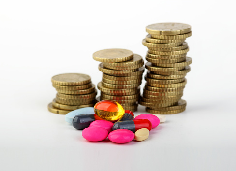 Pile of coins and pills. The concept of rising health care costs