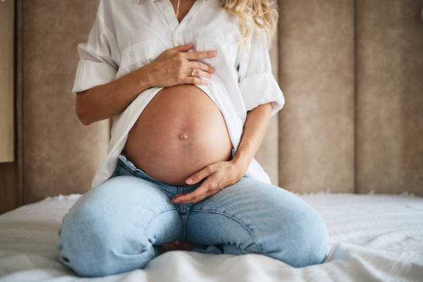 kobieta w ciąży biorąc jej brzuch - human pregnancy abdomen naked human hand zdjęcia i obrazy z banku zdjęć