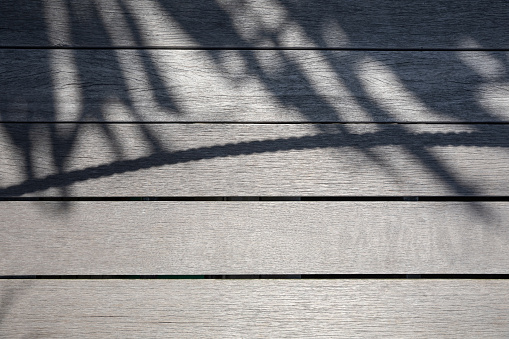 Shadow of palm tree leaves and a rope on wooden background