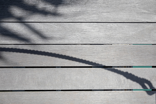 Shadow of the palm leaf and a rope on a wooden surface