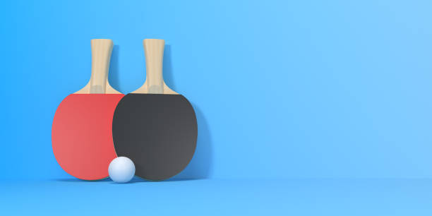 Two table tennis rackets with ball on blue background with copy space