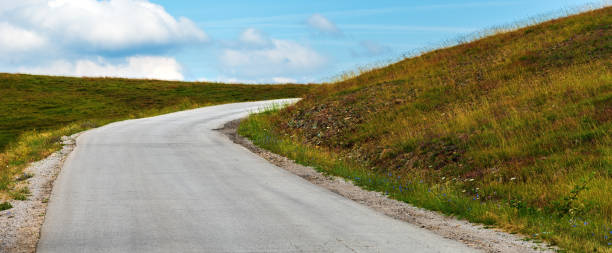 istock Empty winding road disappearing behind the hill 1425845421