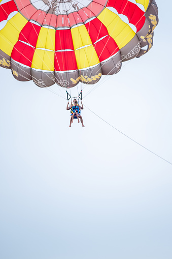 Paraglider pilot with a yellow glider is flying in the clear blue sky, recreational and competitive adventure sport, copy space