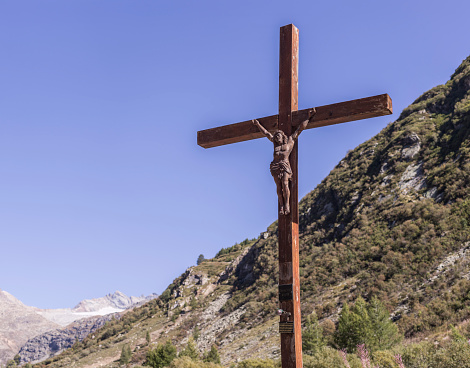 Bonneval-sur-Arc, France - September 18, 2022: Wooden cucified Christ. In the background, the Levanne and the glacier of sources of the Arc river.