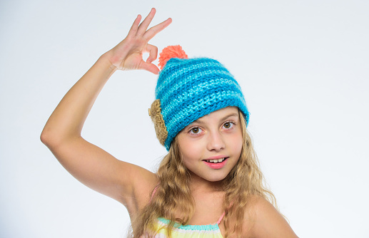 Knitted hat with pompon. Girl long hair happy face white background. Kid wear warm soft knitted blue hat. Difference between knitting and crochet. Fall winter season accessory. Free knitting patterns.