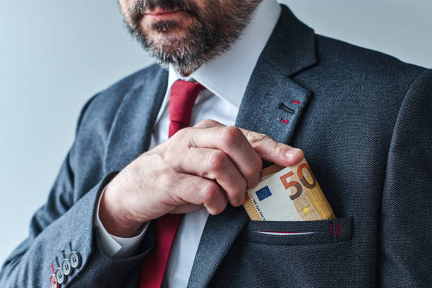 Businessman putting euro cash money into his suit pocket stock photo