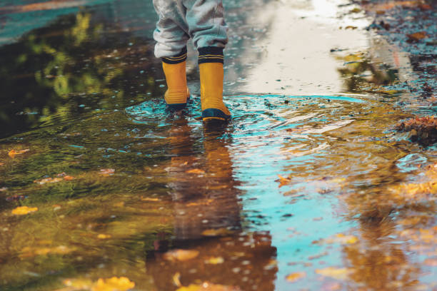 istock Child with rubber rain boots walking on wet sidewalk in autumn afternoon 1425852964