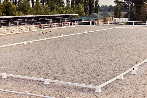 Ready to training. Empty riding sand arena of a horse farm. Concept of sport, competition