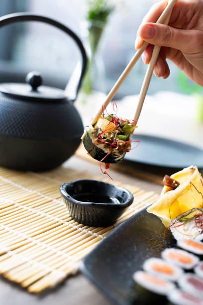 istock Eating sushi. Hands hold sushi chopsticks 1425856545