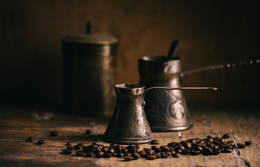 Old coffee pot and coffee bean on rustic wooden table. Vintage oriental coffee on dark background. Still life.