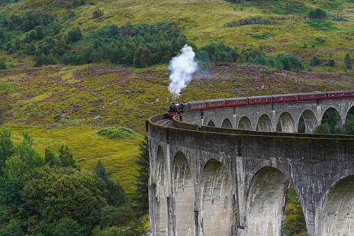 Glenfinnan, Scotland - September 04 2022: The Jacobite steam train crossing the famous Glenfinnan Viaduct. The historic train operates part of the scenic West Highland Line route in the Scottish highlands.