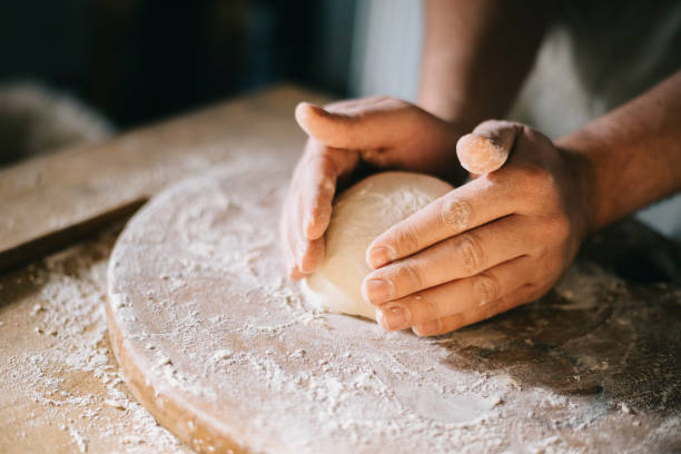 istock Closeup on baker's hands preparing loaf of bread. 1425858386