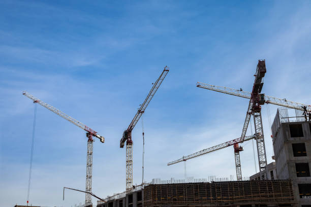 istock Construction cranes work on creation site against blue sky background. Bottom view of industrial crane. Concept of construction of apartment buildings and renovation of housing. Copy text space 1425859727