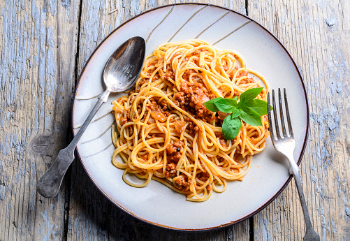Plate of spaghetti bolognese from above. Italian pasta with meat, tomato, cheese and basil closeup. Traditional Mediterranean cuisine recipe. Italian restaurant dish menu.