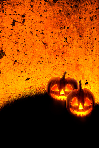 Halloween background wallpaper with jack o lantern scary pumpkins on grunge textured orange backdrop. Halloween party invitation design layout.