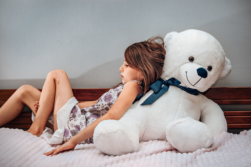 Little girl with a big teddy bear. Problems with children.