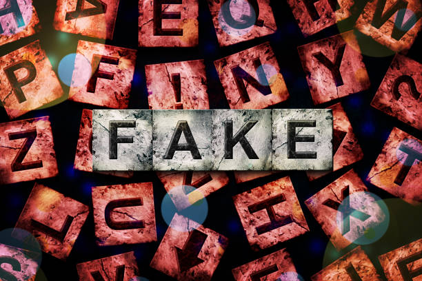 istock Fake, word on an alphabet on stone blocks, on a red background, with different letters. 1425864348