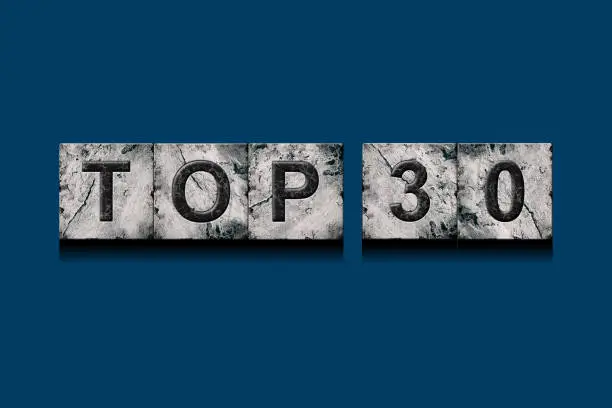 Photo of Top 30, words, above different numbers, on a dark blue background. Alphabet on stone blocks.Rating. Rating concept.