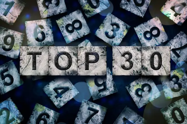 Photo of Top 30, words, above different numbers, on a dark blue background, with different letters. Alphabet on stone blocks.Rating. Rating concept.