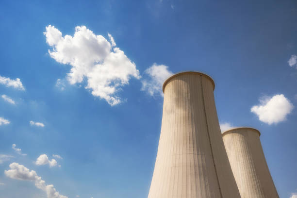 low angle view on industrial smoke stacks against blue sky
