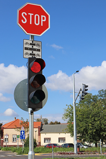 Red traffic light and stop sign at the road crossing