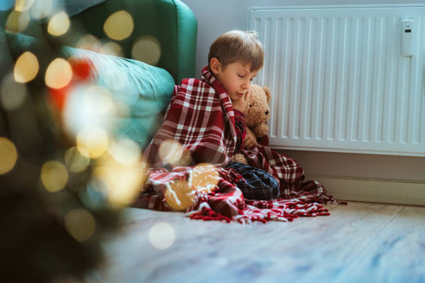 istock cute little boy wrapped id plaid sitting by heater 1425871126