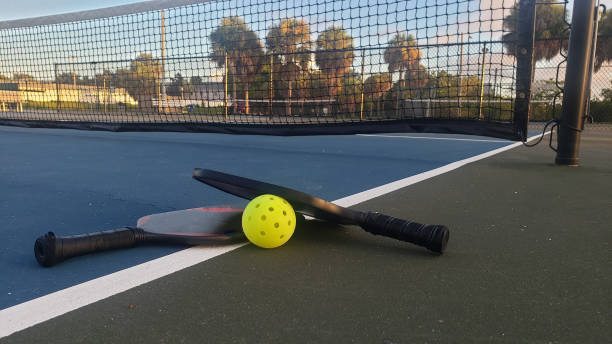 Pickleball Paddles and Ball Low Angle on Court Pickleball paddles and a ball low angle on an empty outdoors court at a public park in St. Petersburg, Florida. paddle ball stock pictures, royalty-free photos & images