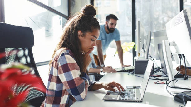 istock Young female programmer sitting at the desk in her office and working . 1425875553