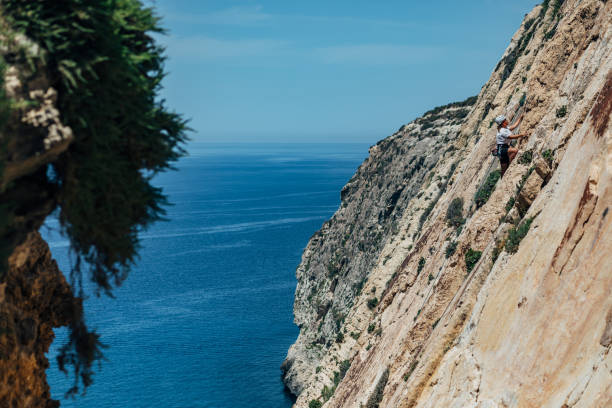 istock Distant view of athletic woman moves forward climbing steep mountain cliffs 1425879072