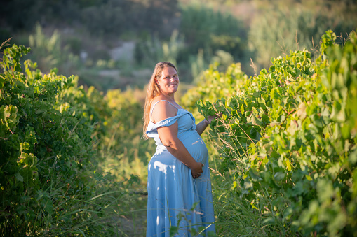 Pregnant woman spending happy time in grape orchard