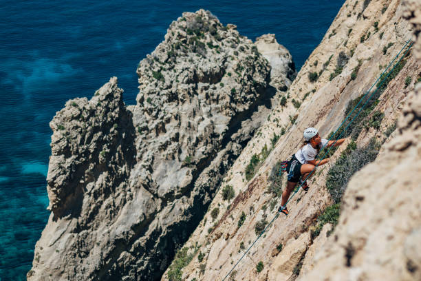 istock Professional female climber overcomes extreme terrain, steep mountain cliffs 1425879348