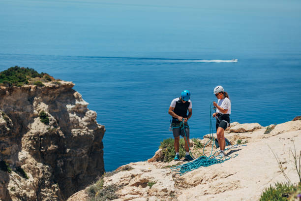 istock A man ties a rope for descending from a mountain, while female climber helps him in this 1425879842