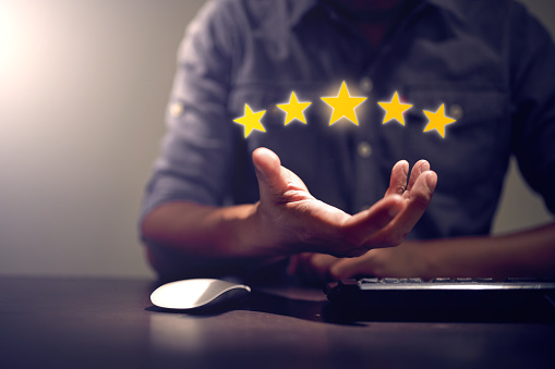 The gesture of the human hand holding five yellow glowing stars icon graphic.  Business Performance Appraisal Concept. Customer Service and Satisfaction Rating.