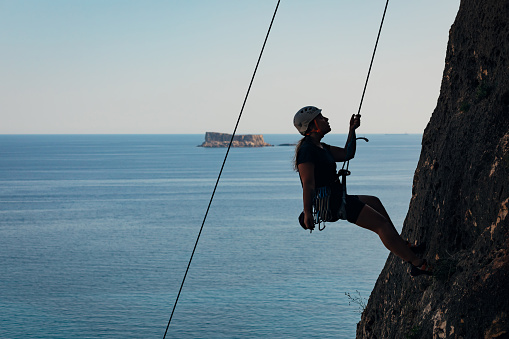 A female climber enjoys the adventure of climbing a mountain using rope