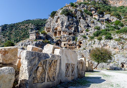 Historical stone theatrical masks bas relief of amphitheater on the background of rock-cut tombs of necropolis in the ancient lycian city of Myra. Territory of modern Demre city, Antalya province, Turkey