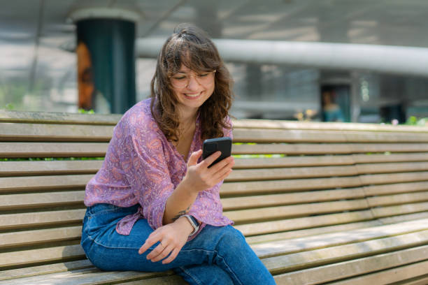 istock Woman sitting on the bench and texting 1425884317