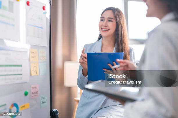 Two Businesswoman Brainstorming Ideas On Whiteboard With Colleague Female Business Partners Having Brainstorming Session About Financial Budget In Startup Meeting Room Stock Photo - Download Image Now