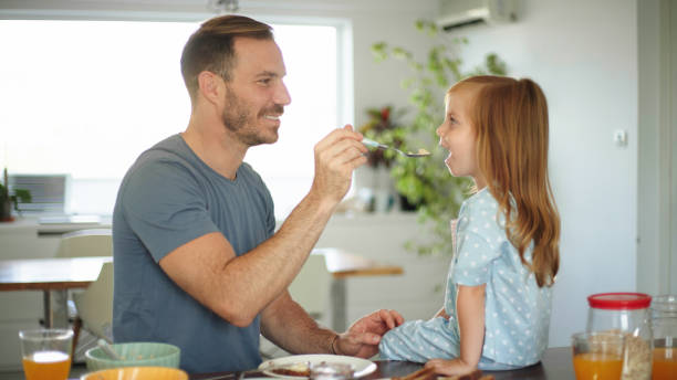 istock Father feeding his little girl in the kitchen 1425889355