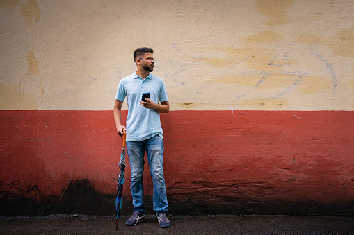 Young Indian man holds and uses mobile phone on the street in Mumbai