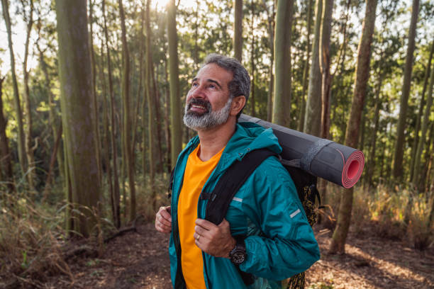 Senior man walking through the woods-hiking Beautiful day in nature. Mature man prepared for hiking, enjoy walks through the woods 50 59 years stock pictures, royalty-free photos & images