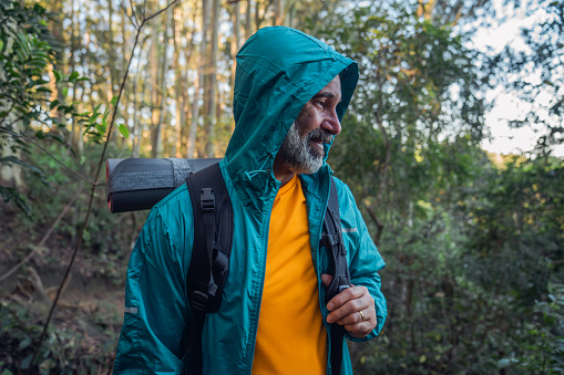 Portrait of an elderly man, casually dressed, hiking in a mountain forest